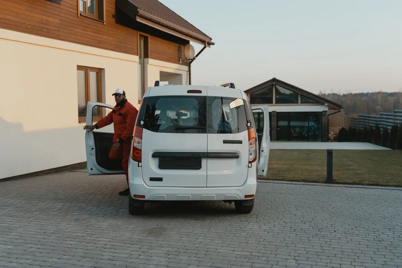 A home-service technician stepping out of his van in a customer's driveway